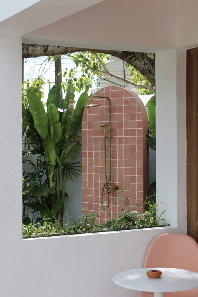 Open-sky garden shower with pink tiles and tropical plants
